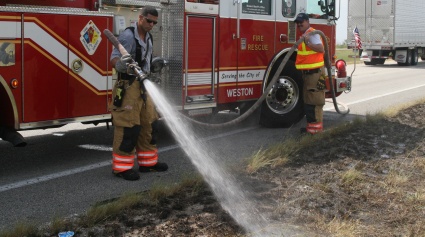 Broward Sheriff Firefighter Gonzalo Curbelo (left) and Driver/Engineer Jim Harkins douse a hot spot along U.S. 27 Monday.